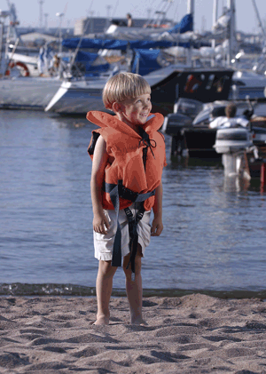Boy at boat harbour  in life jacket grinning 
