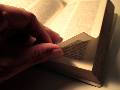 A man turns the pages of a Bible as he reads