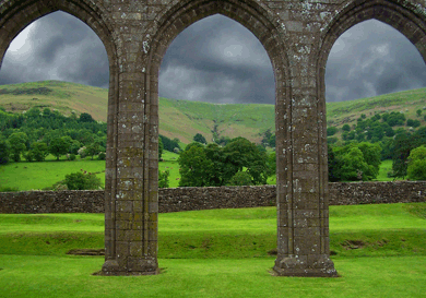 Green hills between the arches of a ruined priory in Wales