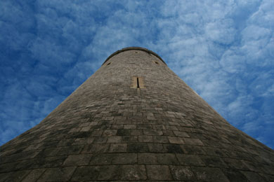 View shows ominous stone tower of Windsor Castle with arrow slits soaring into blue sky.