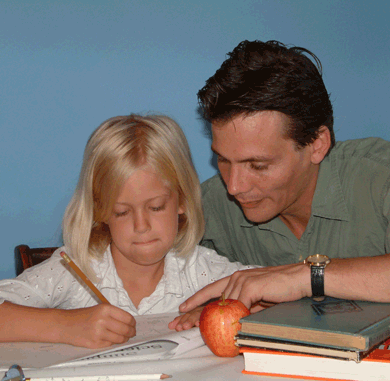 Little girl doing homework with teacher's help