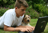 Boy with laptop and dog in garden